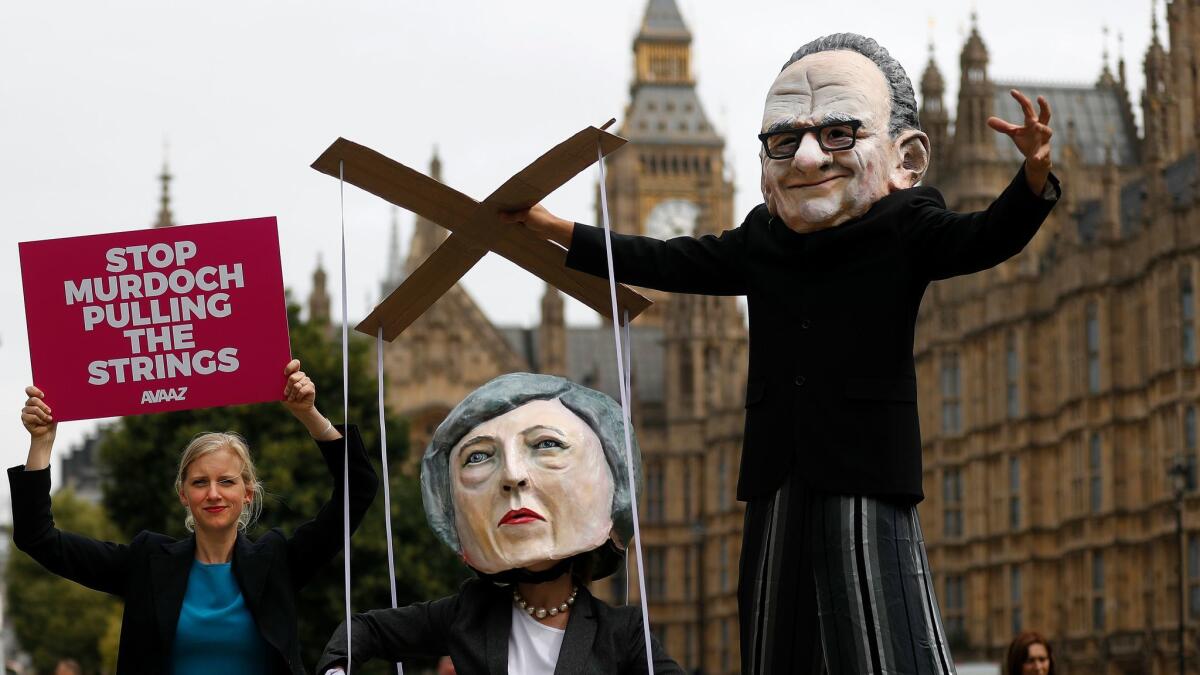 Activists outside British Parliament in London last month mock Rupert Murdoch and Prime Minister Theresa May to protest 21st Century Fox's $15-billion bid to control satellite TV service Sky.