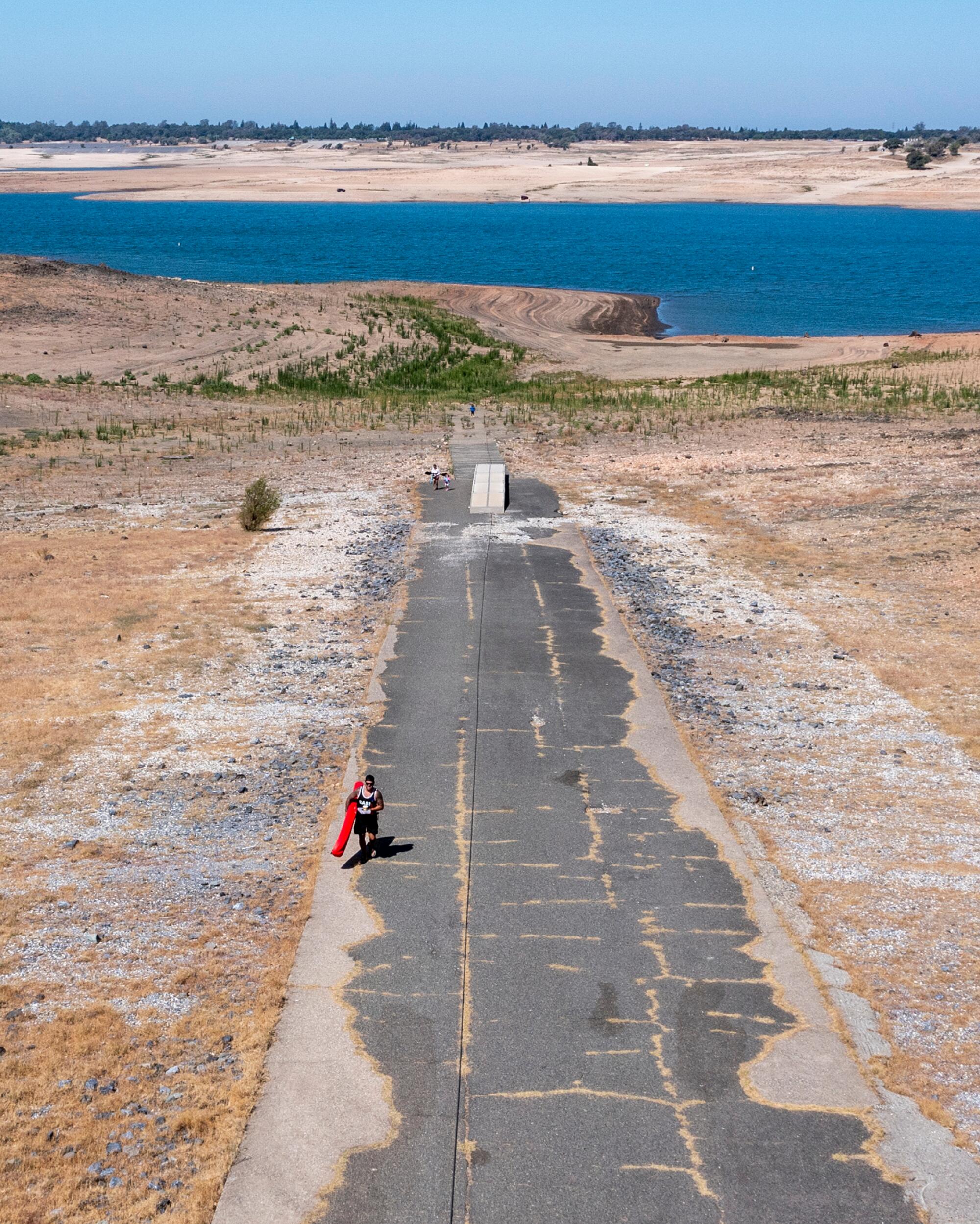 A kayaker carries his kayak hundreds of feet up a ramp from the lakeshore to a parking area at Folsom Lake.