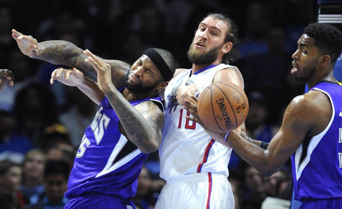 Clippers center Spencer Hawes gets tangled with Kings center DeMarcus Cousins, left, as they battle for a rebound along with Sacramento's Jason Thompson.