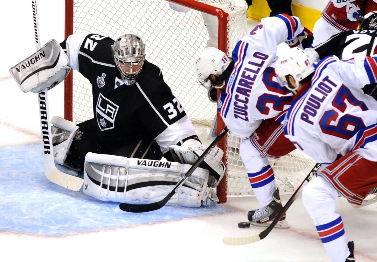 Kings goalie Jonathan Quick prevents New York Rangers teammates Mats Zuccarello, center, and Benoit Pouliot from jamming the puck past him during the third period of Game 1 of the Stanley Cup Final at Staples Center.