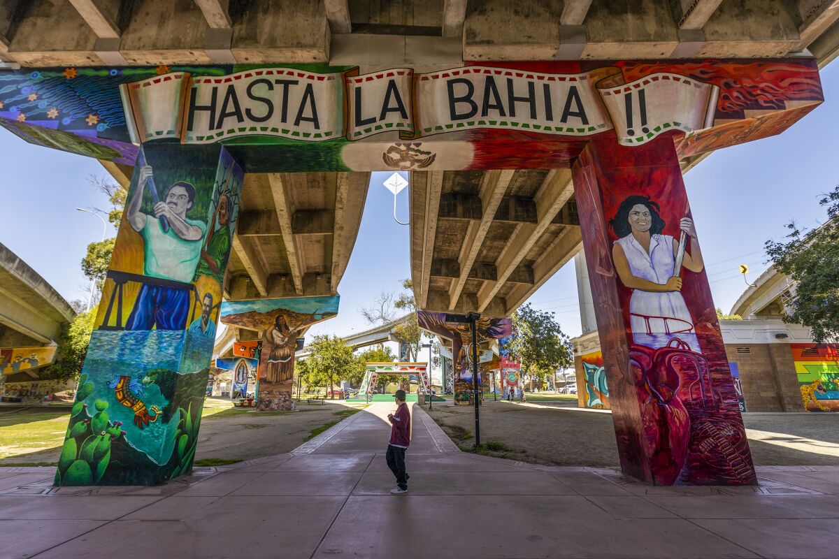 A person walks past a mural painted on the underside of a bridge at Chicano Park