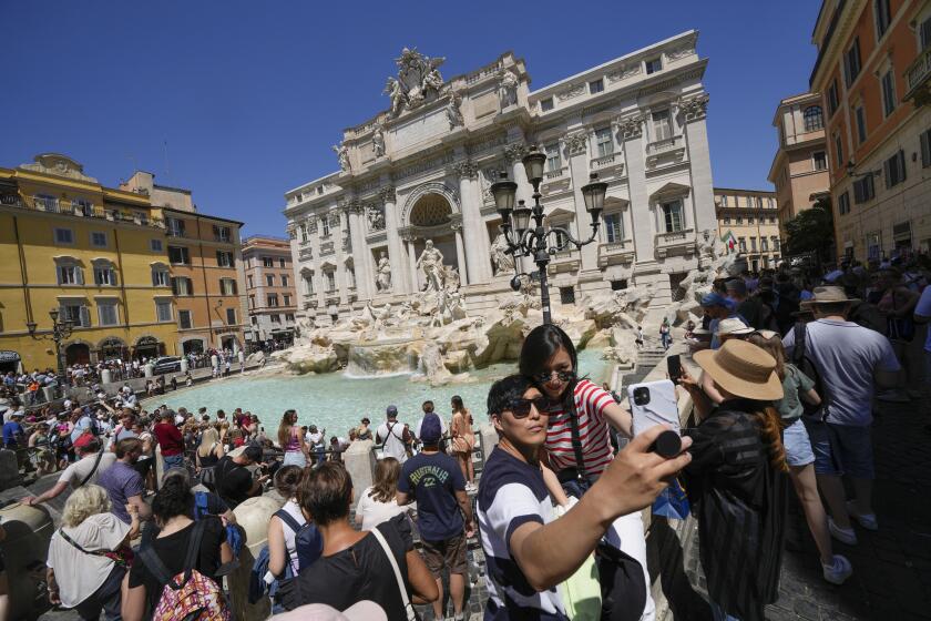 Tourists take a selfie in front of the Trevi Fountain, in Rome.