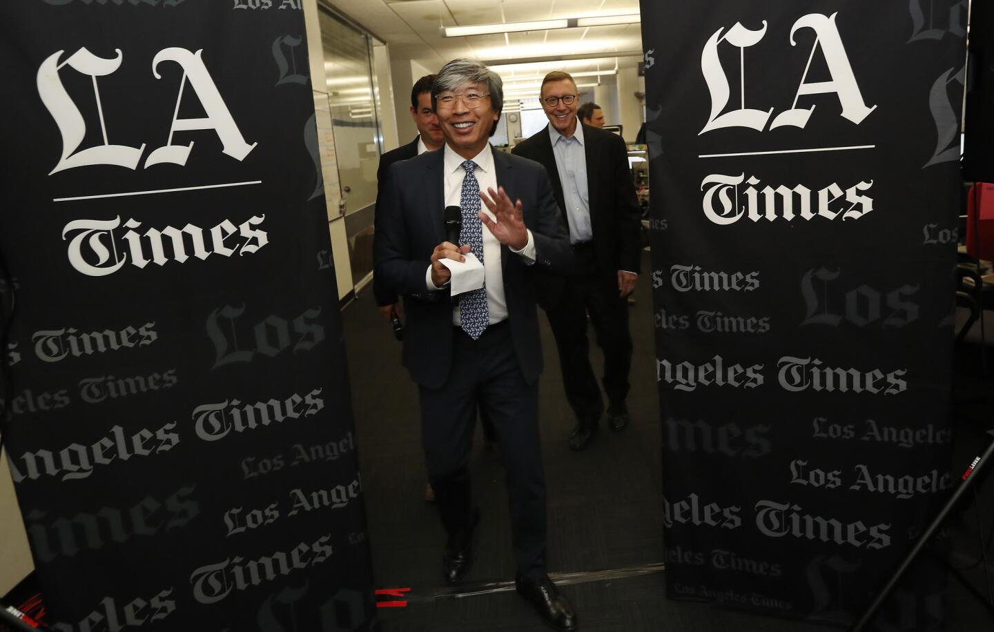 Dr. Patrick Soon-Shiong, foreground, in the Los Angeles Times newsroom Monday. He has taken the title of executive chairman of The Times and California Times, the new corporate moniker for the group of publications that he acquired. Behind him are Chris Argentieri, left, currently the general manager of The Times who will become chief operating officer of California Times, and Norman Pearlstine, who has been named executive editor of The Times.