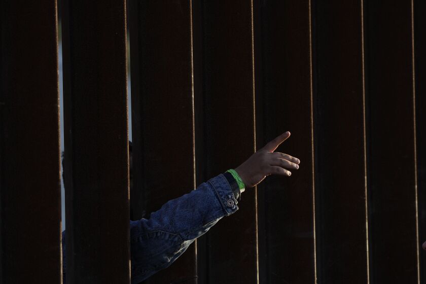 A man gestures as he waits with others to apply for asylum between two border walls Thursday, May 11, 2023, in San Diego. Many of the hundreds of migrants between the walls that separate Tijuana, Mexico, with San Diego have been waiting for days to apply for asylum. Pandemic-related U.S. asylum restrictions, known as Title 42, are to expire May 11. (AP Photo/Gregory Bull)