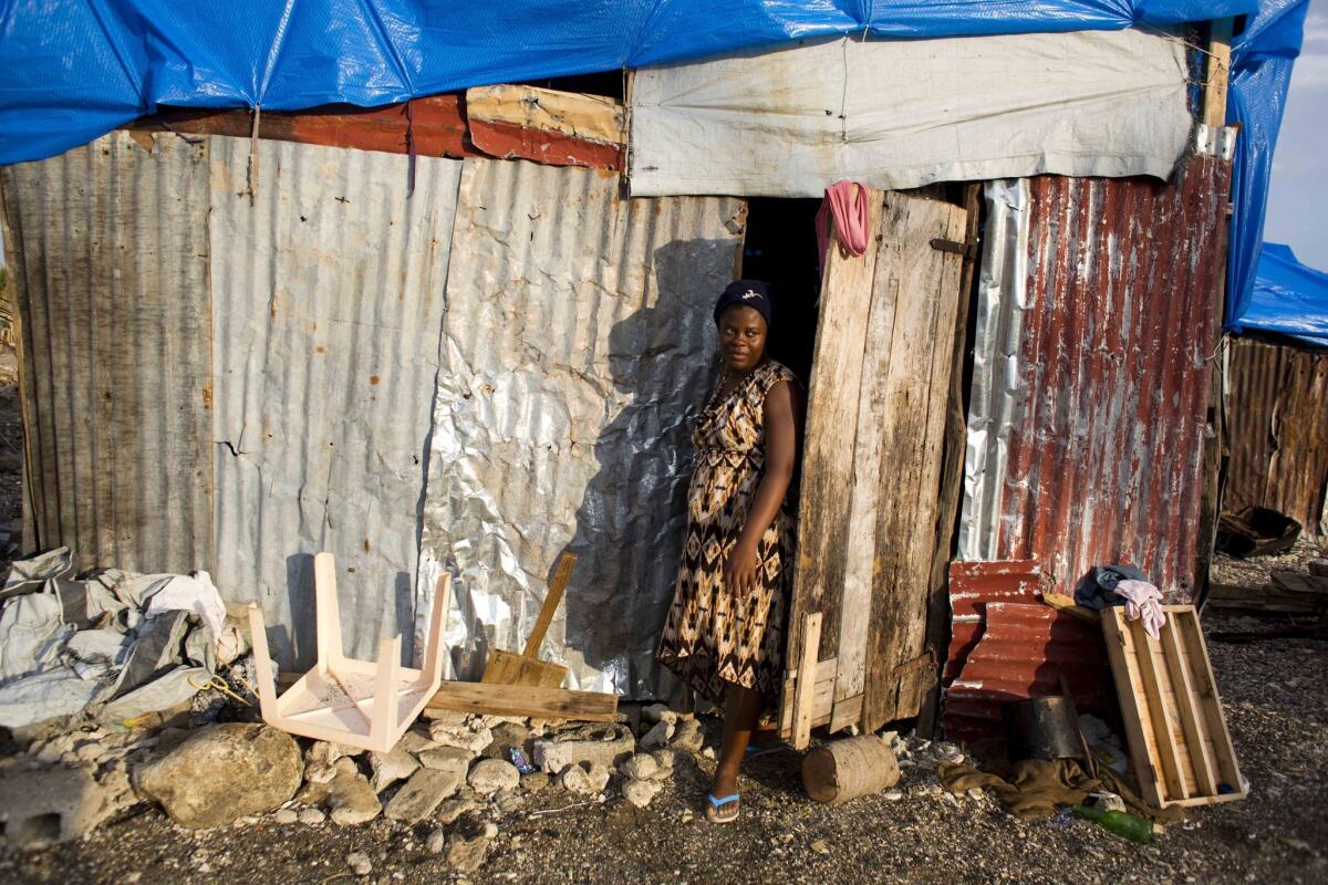 En esta imagen del 31 de octubre de 2016, Nathanaelle Bernard, embarazada de 7 meses, sale del cobertizo donde vive ahora, después de que su casa quedara destruida por el huracán Matthew, en Coteaux, Haití. (AP Foto/Dieu Nalio Chery)