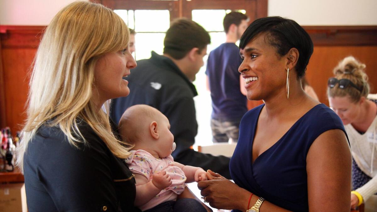 California Assembly candidate Buffy Wicks, left, holds her daughter as she speaks with Kimberly Ellis, then a candidate for state Democratic Party chair, at a May campaign event in Oakland.