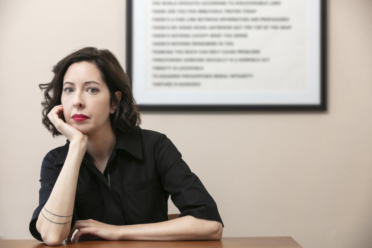 A woman leaning her chin on her hand in front of a blurry framed text