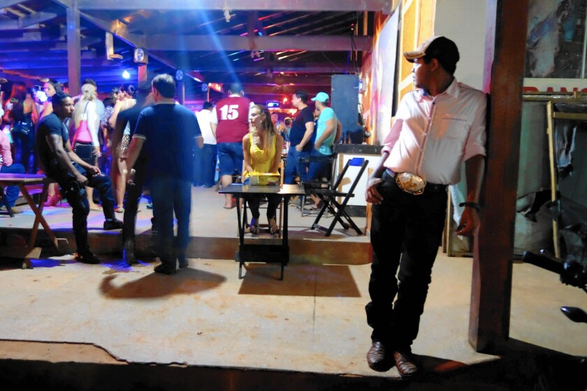 An open-air nightclub in Novo Progresso, Brazil, fills the air with the worries of country music -- love, loss, rebellion. Alexandra Loch, at the table in the background, charges patrons as they enter.