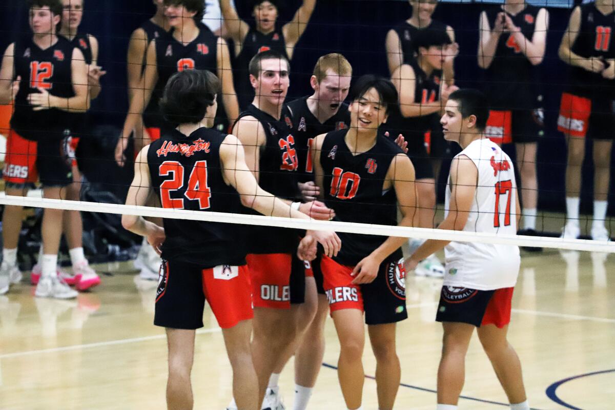 The Huntington Beach boys' volleyball team celebrates after winning against Newport Harbor on Tuesday.