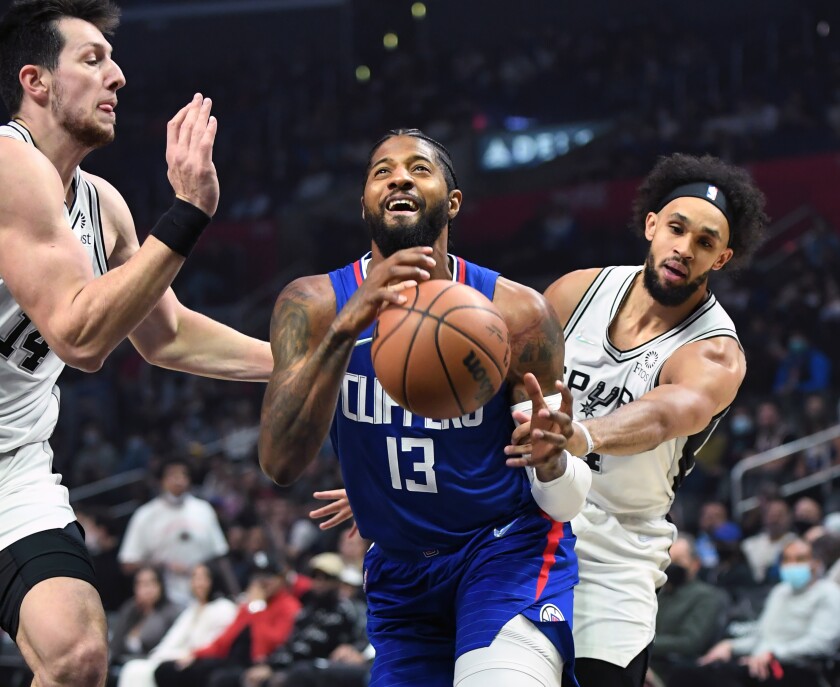 The Clippers' Paul George is fouled by the Spurs' Derrick White, right, while driving to the basket