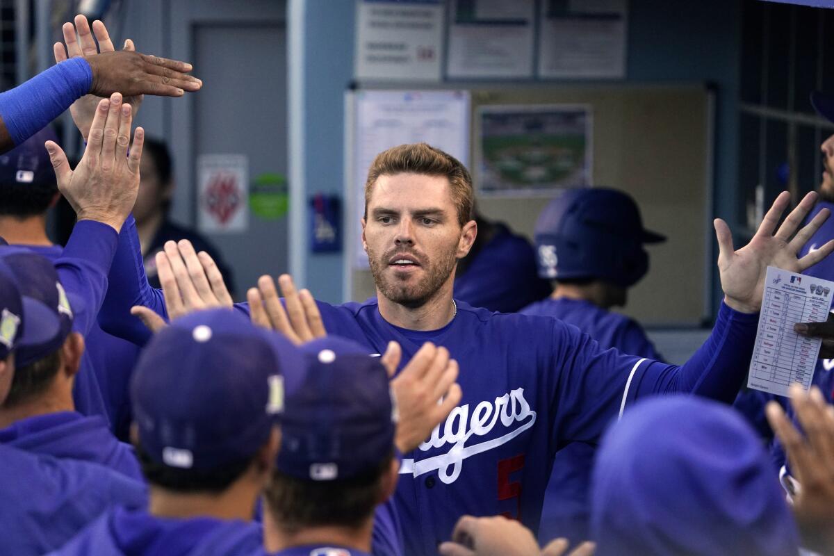 Los Angeles Dodgers' Freddie Freeman is congratulated by teammates in the dugout.