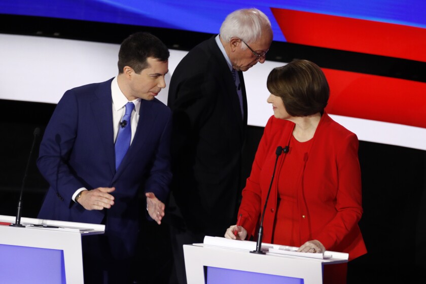 Democratic presidential candidates former South Bend Mayor Pete Buttigieg, left, and Sen. Amy Klobuchar, D-Minn., talk while Sen. Bernie Sanders, I-Vt., heads off stage at a break Tuesday, Jan. 14, 2020, during a Democratic presidential primary debate hosted by CNN and the Des Moines Register in Des Moines, Iowa. (AP Photo/Patrick Semansky)