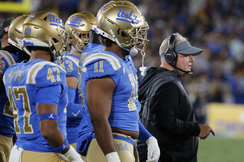 UCLA head coach Chip Kelly stands in front of players on the sideline