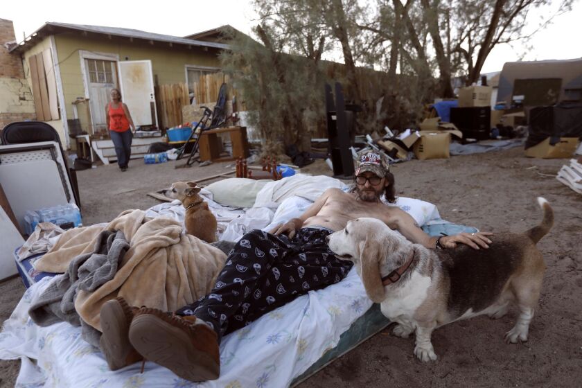 Dan Tolbert, 62, spends time with his dogs as he and his wife, Ronnie, 60, prepare to bed down for the night on a pair of mattresses in front of their earthquake-damaged home in Trona on July 10. Their night was interrupted when a scorpion crawled on their mattresses and they ended up spending the night in their truck. "If we keep feeling tremors tomorrow we'll be out here again," Ronnie said.