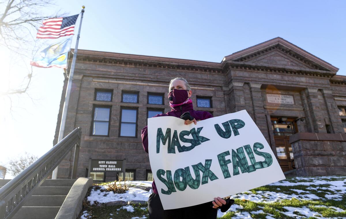 Jenae Ruesink holds a sign demanding a mask mandate from Sioux Falls city council.