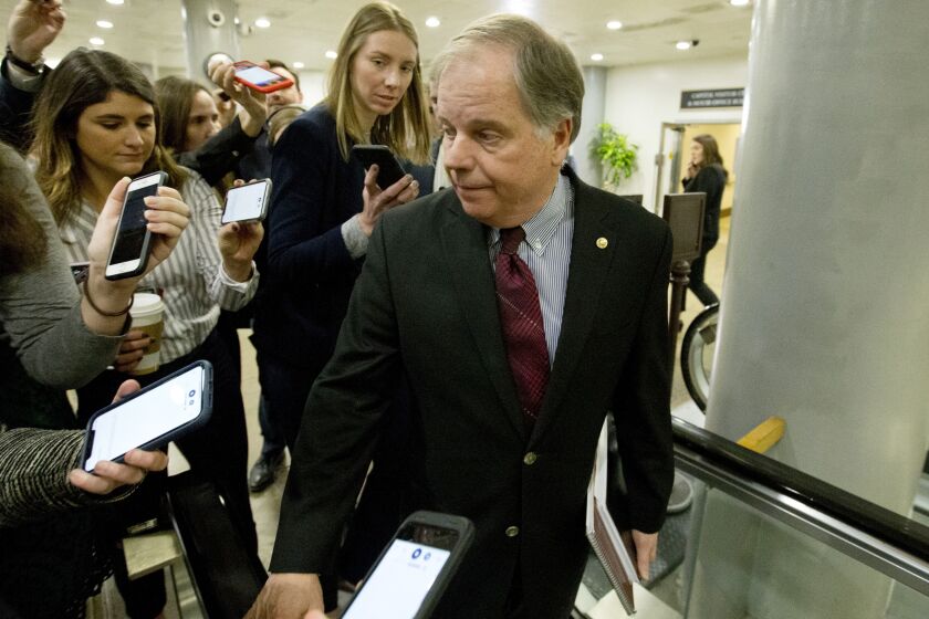 Sen. Doug Jones, D-Ala., talks to reporters as he walks to attend the impeachment trial of President Donald Trump on charges of abuse of power and obstruction of Congress, Tuesday, Jan. 28, 2020, on Capitol Hill in Washington. (AP Photo/Jose Luis Magana)