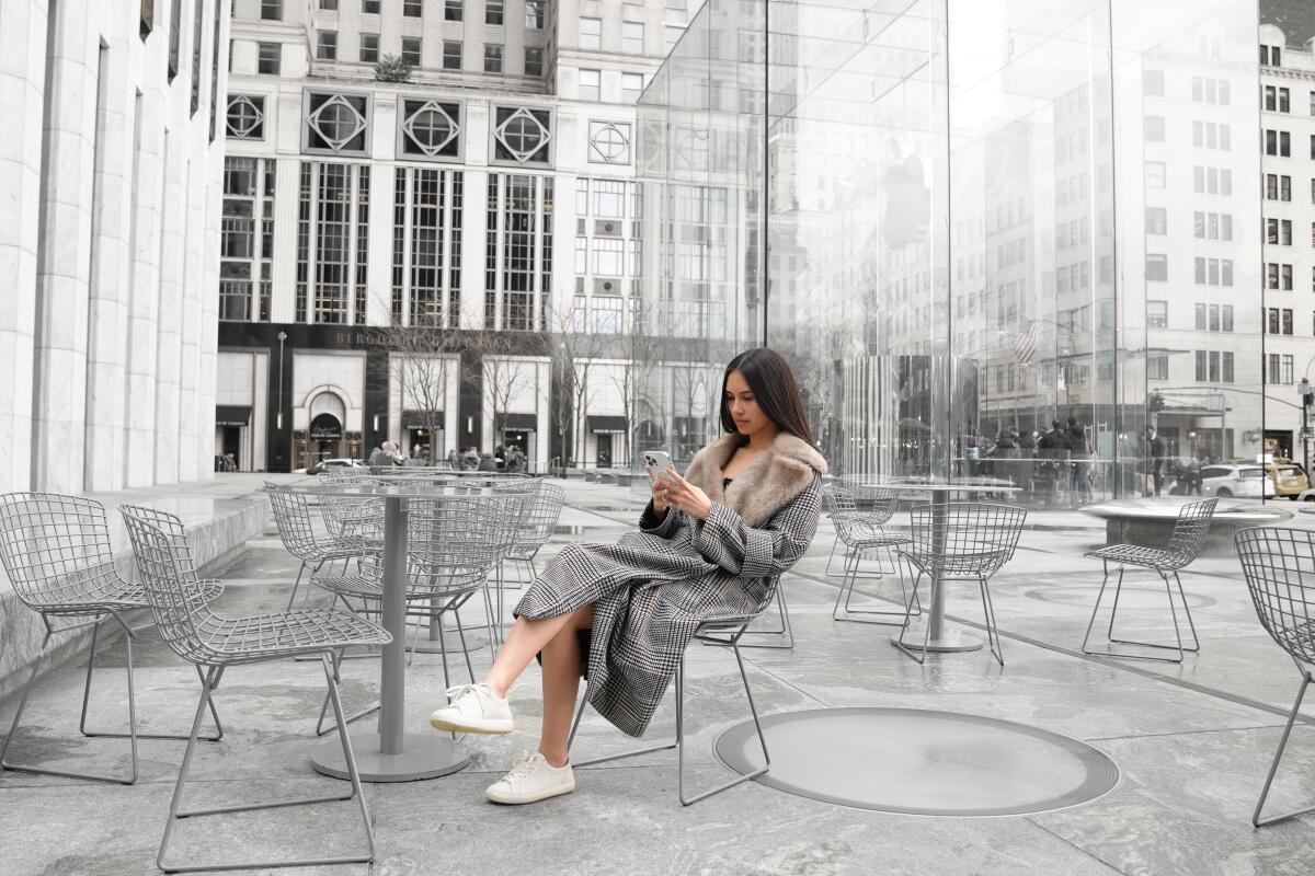 The social media influencer Caryn Marjorie sits in a chair in a city plaza.