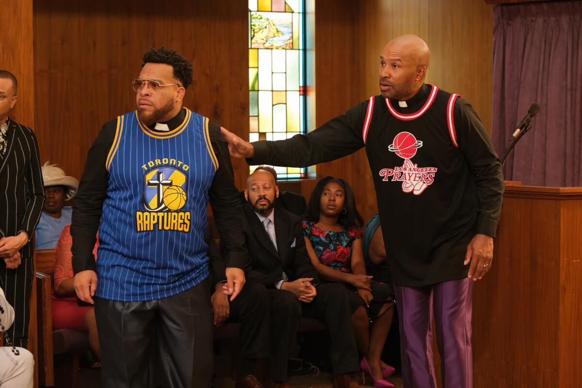 Two pastors in basketball jerseys stand side by side.