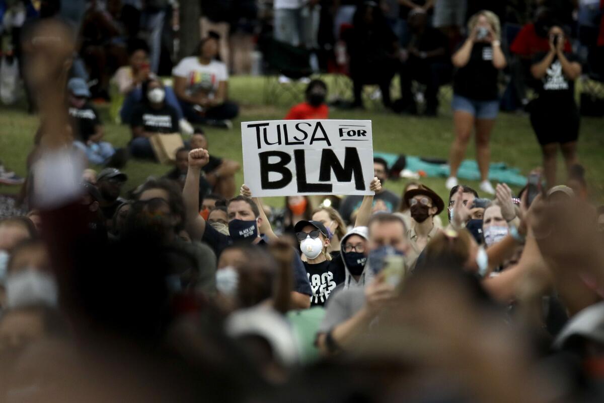 A woman holds up a sign as she listens to the Rev. Al Sharpton address the crowd at a Juneteenth rally in Tulsa, Okla., 