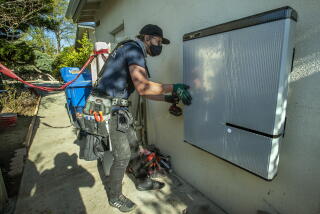 GRANADA HILLS, CA - JANUARY 04, 2020: Oliver Walker, a foreman for the solar company, Sunrun, installs a 215 pound lithium-ion battery at a home in Granada Hills. Solar panels were also installed on the roof of the home. (Mel Melcon / Los Angeles Times)