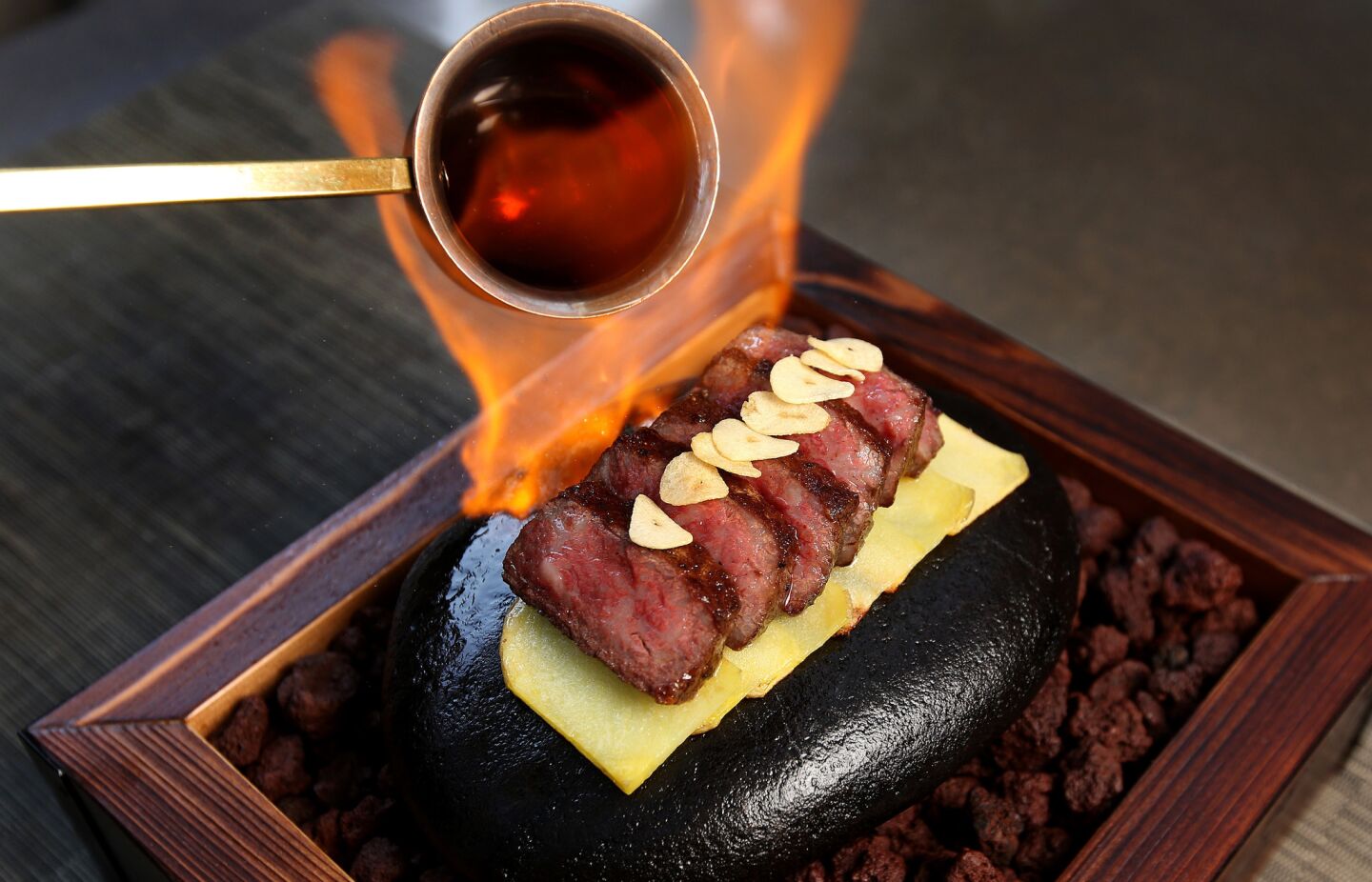 Satsuma Wagyu Ribeye Stone Steak served on a hot stone and flambéed with Hennessy.