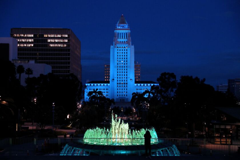 LOS ANGELES, CA -- APRIL 10: Los Angeles City Hall shown from Grand Park in downtown displays blue lights to show support for health care workers and first responders on the front lines against the coronavirus pandemic on Friday, April 10, 2020, in Los Angeles, CA. (Gary Coronado / Los Angeles Times)