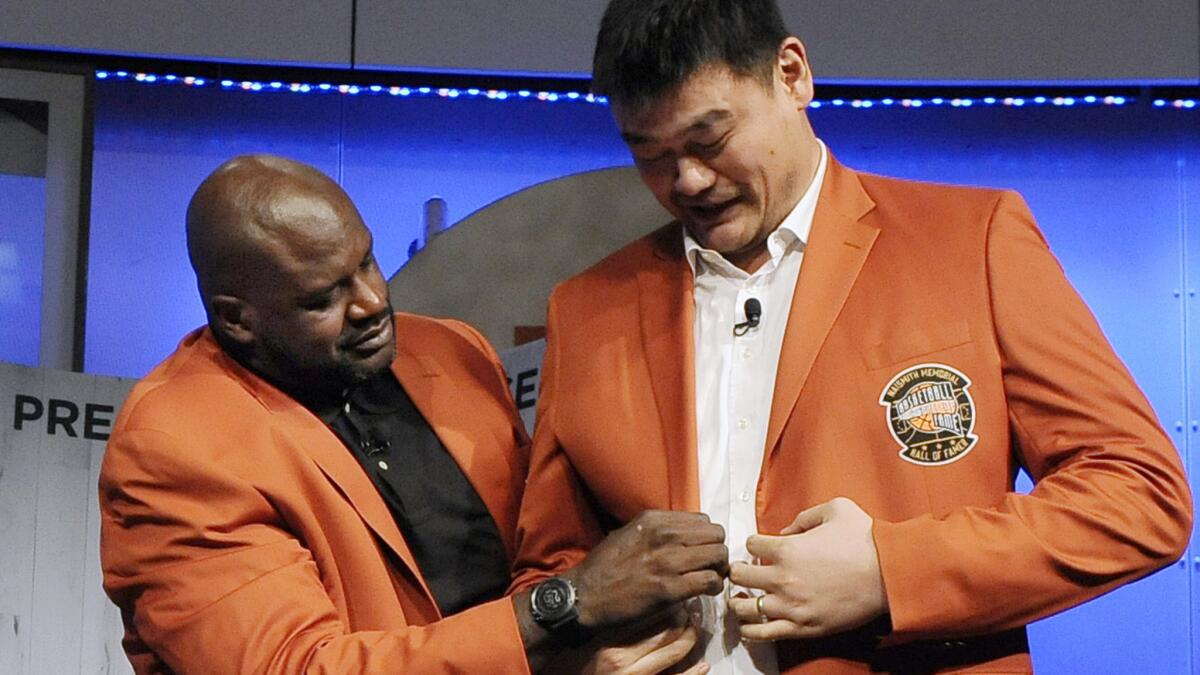 Shaquille O'Neal helps Yao Ming with his jacket during a news conference at the Basketball Hall of Fame on Thursday.
