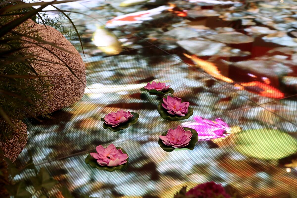 Floral decorations are placed atop a high-definition digital pond displaying swimming koi fish.