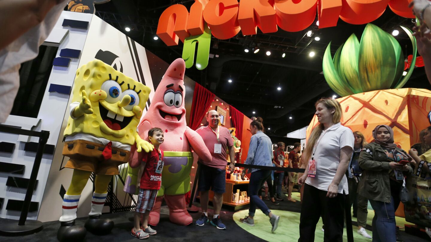 Sponge Bob Squarepants and Patrick pose with a fan for a photo at the Nickelodeon booth during the opening day of Comic-Con International 2017.