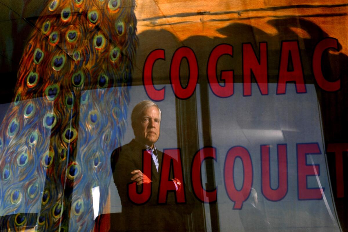Alan Snyder, founder and managing partner of Shinnecock Partners, is captured in a reflection of a poster of a painting by French artist Camille Bouchet titled "Cognac Jacquet" at his office in Los Angeles.