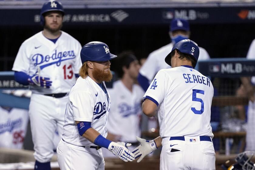Los Angeles Dodgers' Corey Seager (5) is met at home plate by Justin Turner after Seager's solo home run against the Milwaukee Brewers during the seventh inning in Game 1 of a National League wild-card baseball series Wednesday, Sept. 30, 2020, in Los Angeles. (AP Photo/Ashley Landis)