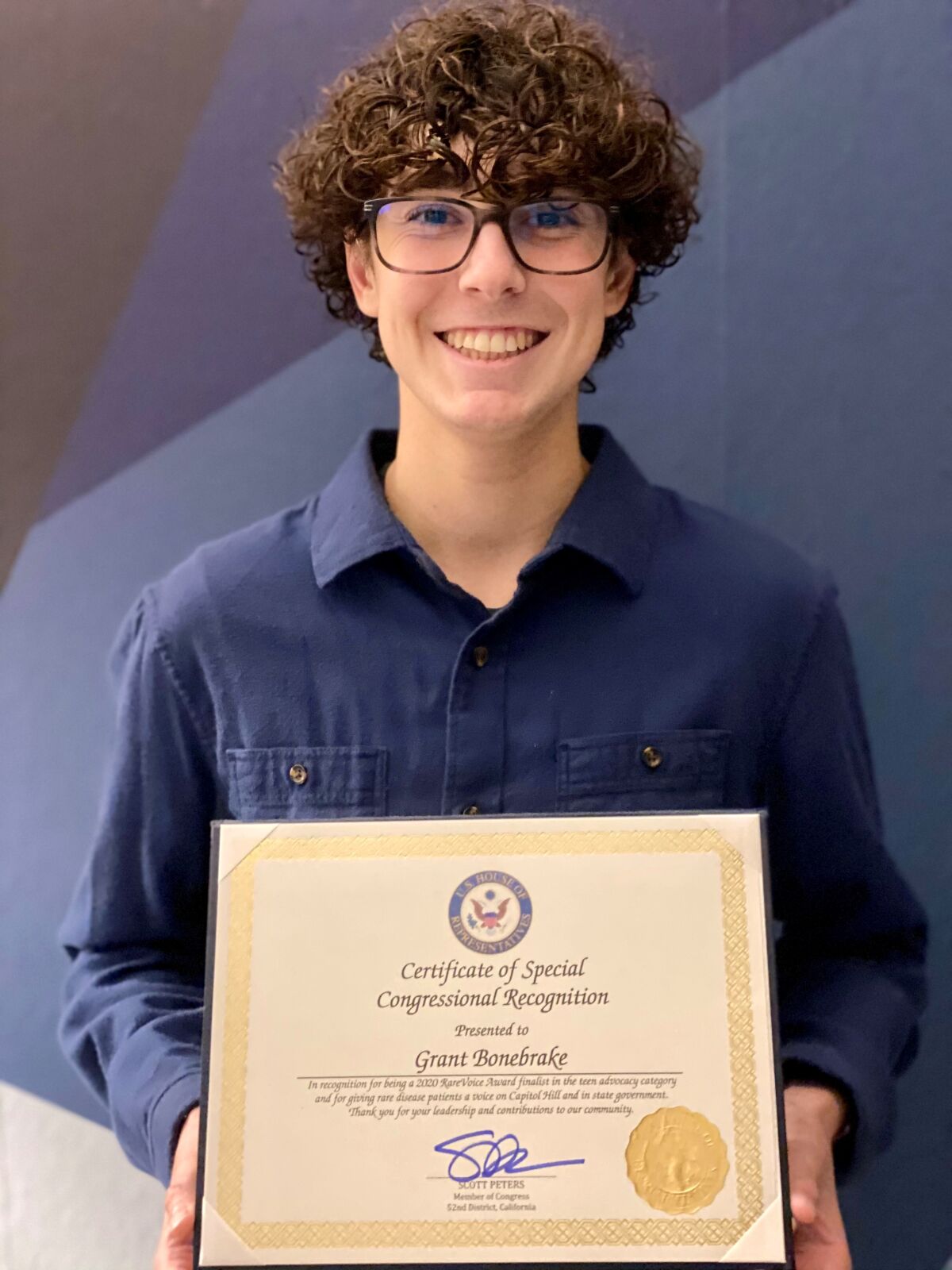 Grant Bonebrake holds a certificate from Congressman Scott Peters congratulating him on the Rare Voice Award.