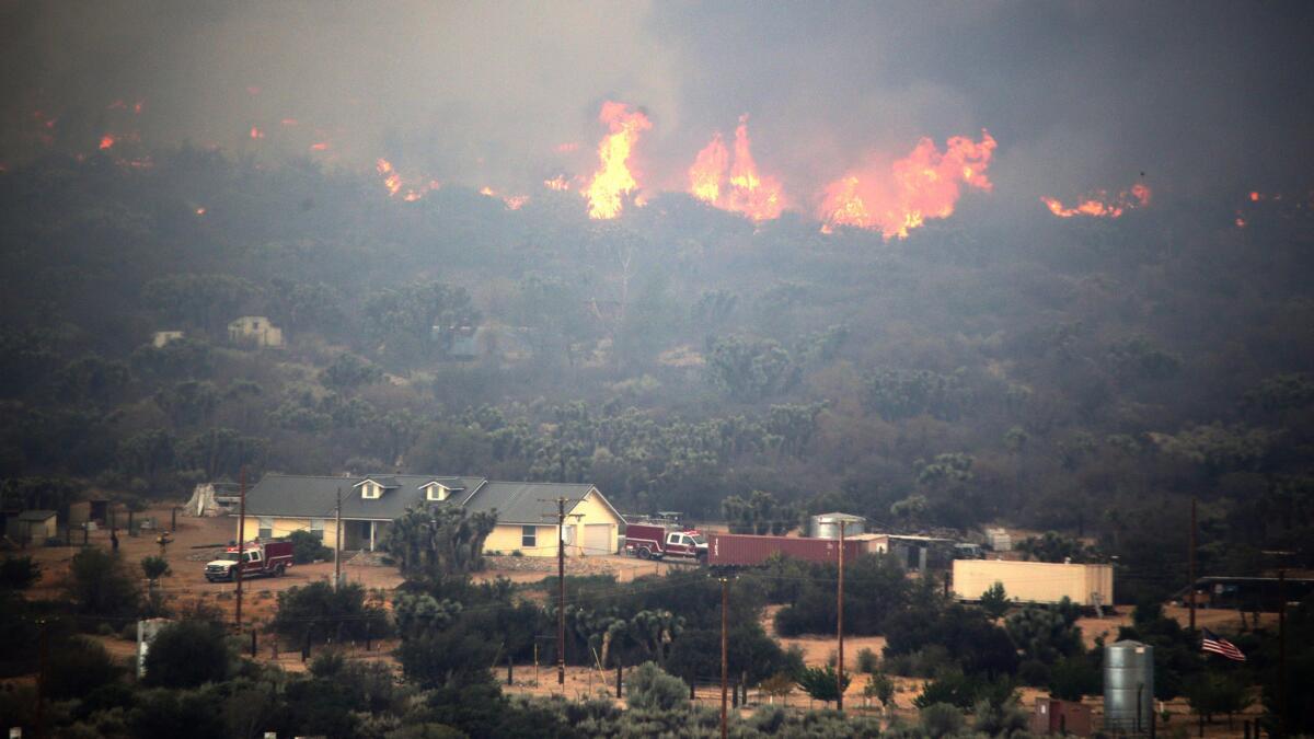 Fire fighters work to protect a home threatened by the Blue Cut Fire near Phelan, Calif. in August.