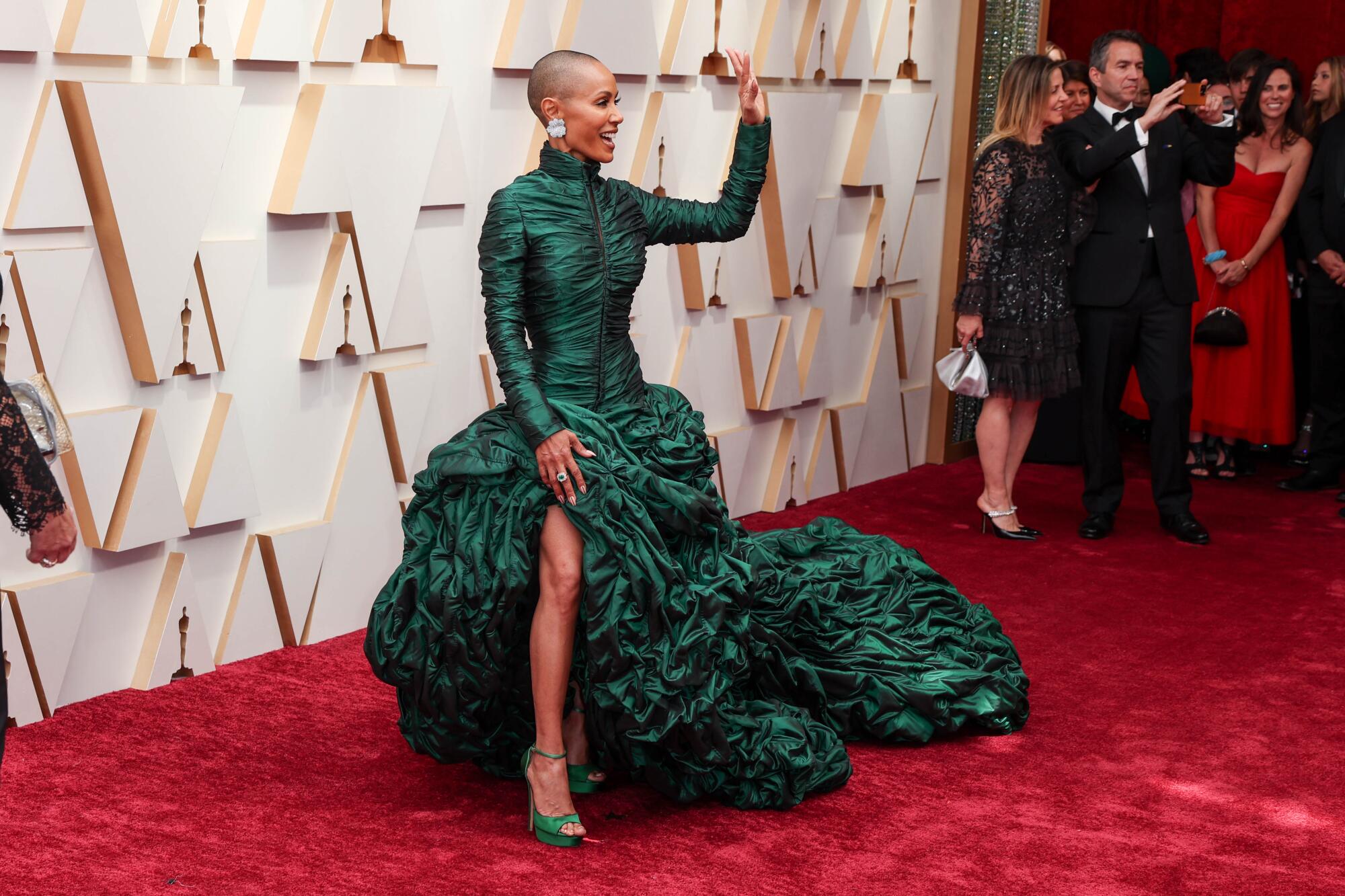 A woman in large silver earrings and a flowing dark-green gown 