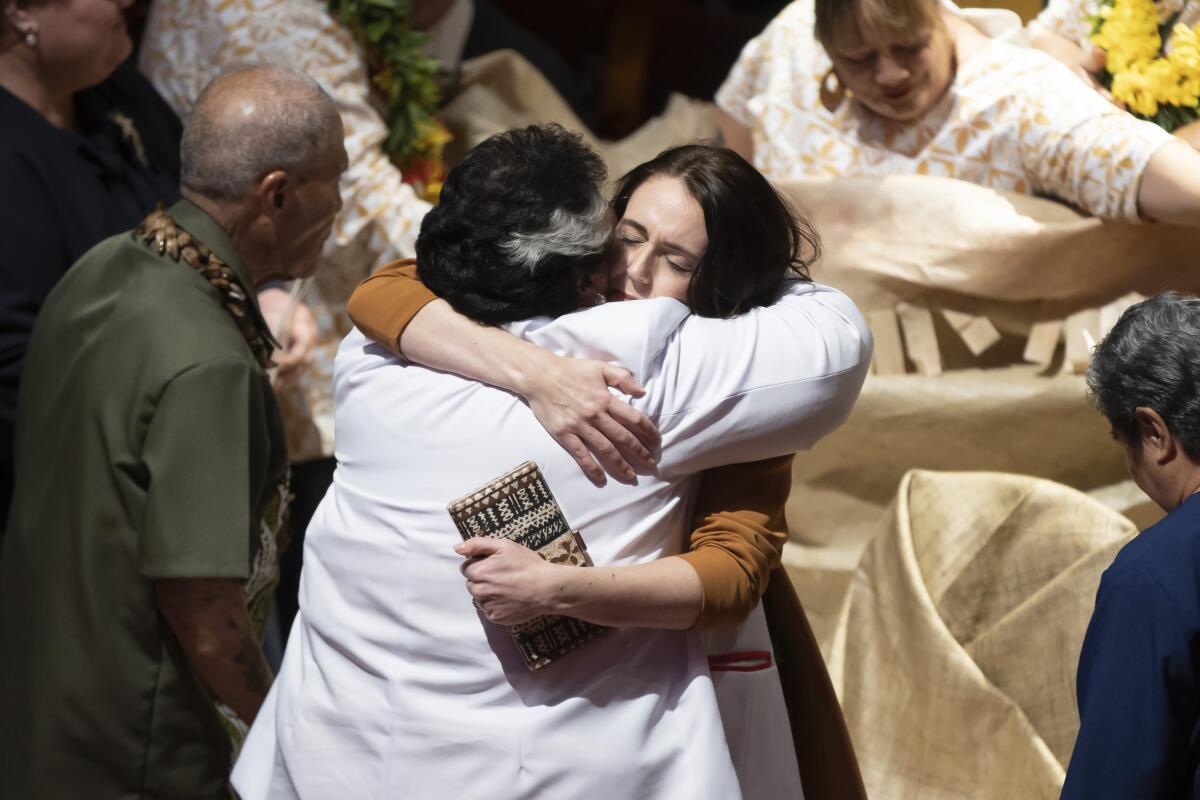 New Zealand Prime Minister Jacinda Ardern, center right, is hugged during a ceremony in Auckland, Sunday, Aug. 1, 2021, to formally apologize for a racially charged part of the nation's history known as the Dawn Raids. The Dawn Raids are known as the time when the Pasifika people were targeted for deportation in the mid-1970s during aggressive home raids by authorities to find, convict and deport visa overstayers. (Brett Phibbs/New Zealand Herald via AP)