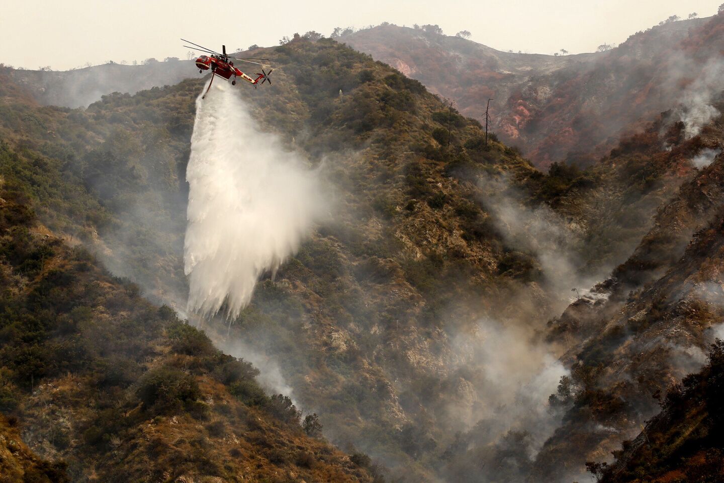 A helicopter makes water drops on Spinks Canyon above Duarte on Tuesday as two brush fires burn dangerously close to one another in Duarte and Azusa.