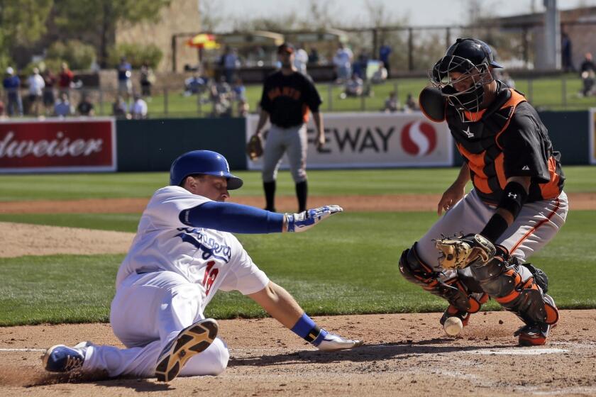 Tim Federowicz, left, scores as San Francisco Giants catcher Guillermo Quiroz bobbles the throw during a spring training game last month.