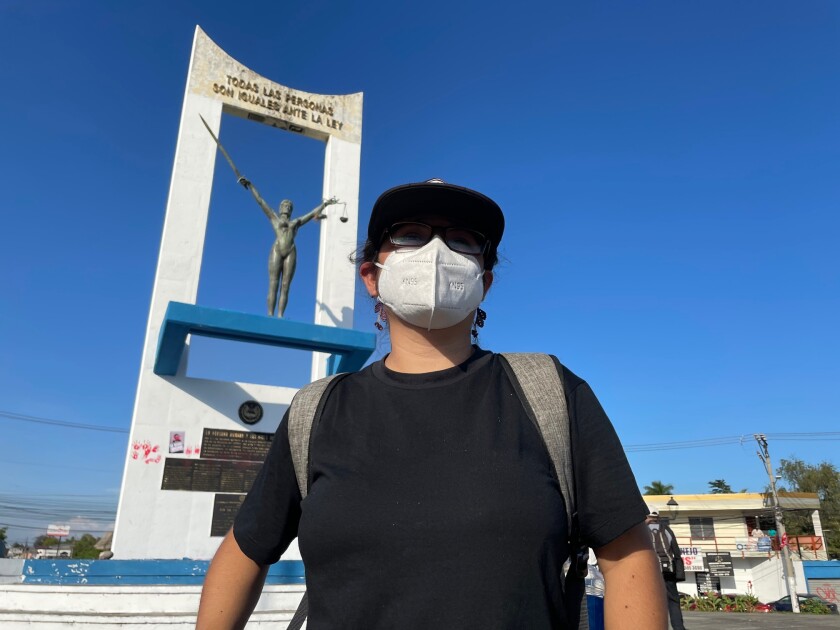 A woman stands in front of a monument in San Salvador.