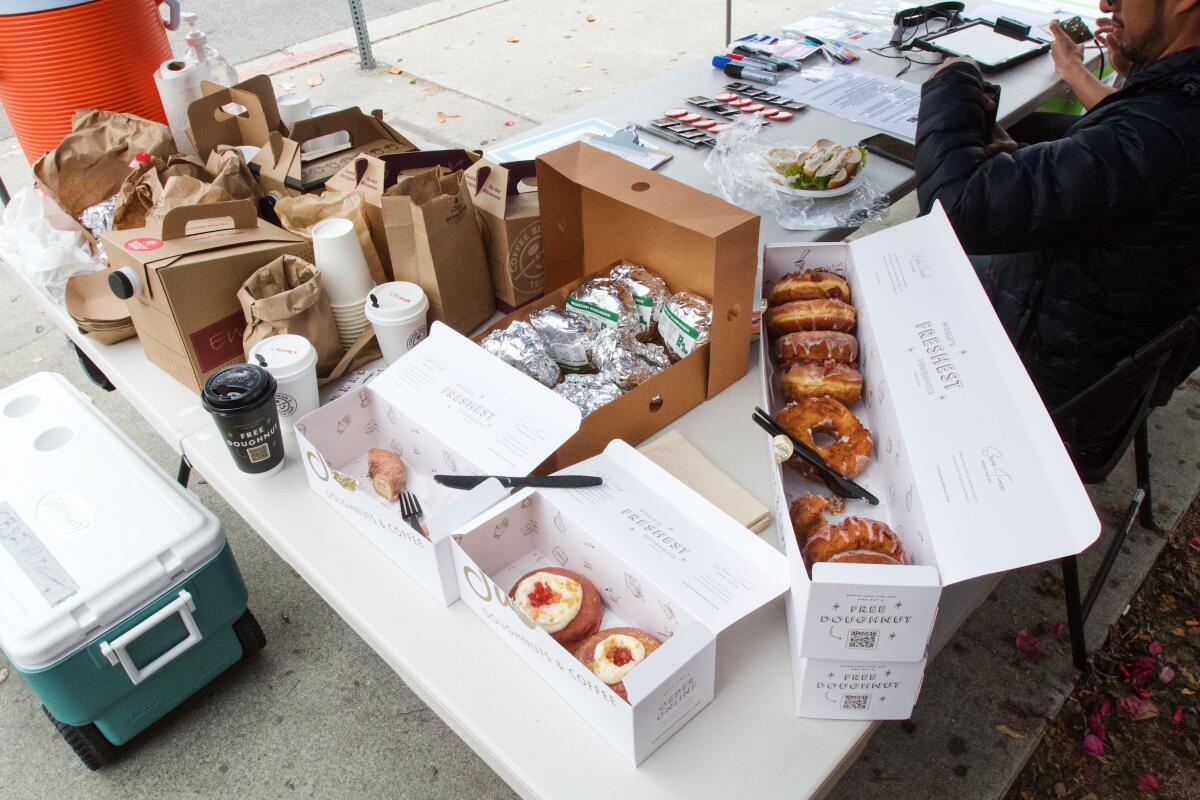 A table of delivered food at the CBS Television City picket line: doughnuts, breakfast tacos, bagel sandwiches and coffee
