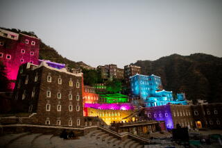 Stone buildings illuminated in rainbow colors in a mountainous setting