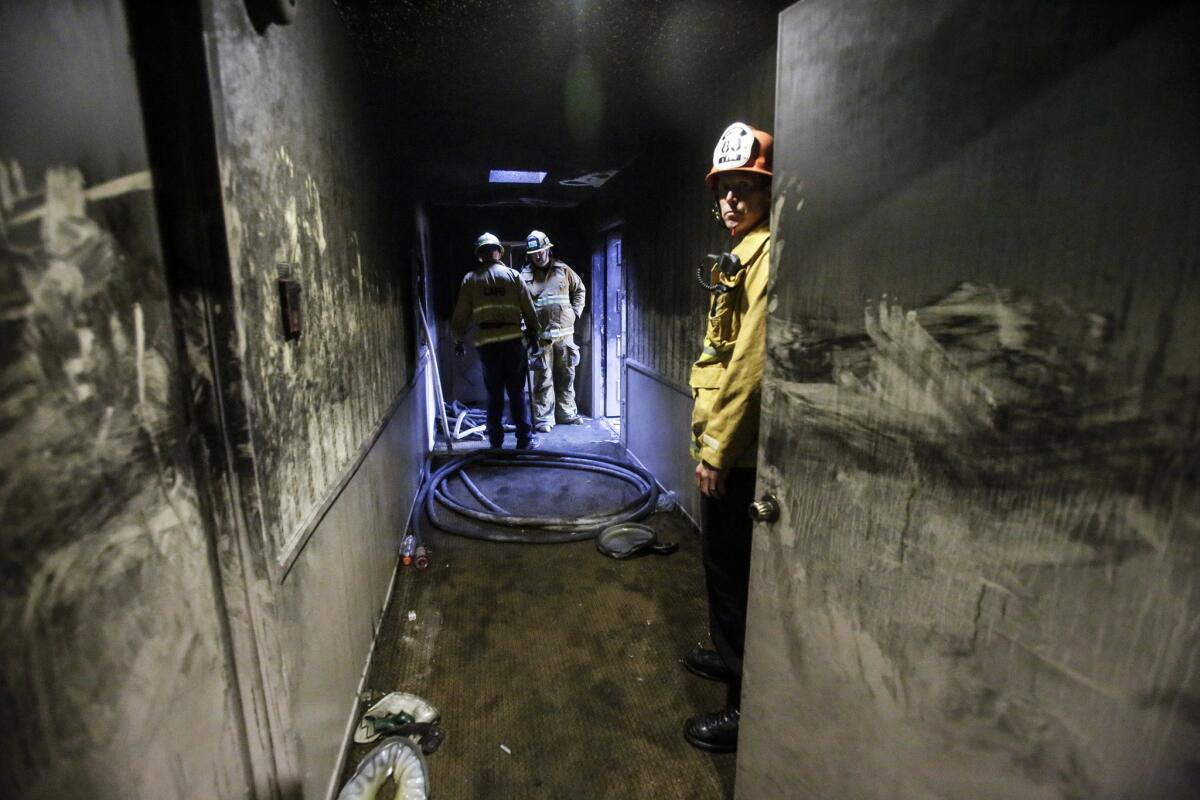 Los Angeles Fire Captain R.J. Kilpatrick, right, stands by the blackened hallway in the 5300 block of Lindley Avenue in Encino, where two people died in a fire.