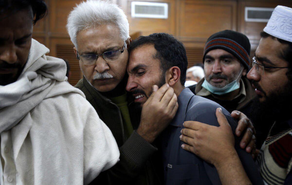 A Pakistani at a hospital in Peshawar comforts another man mourning a relative killed Saturday during a rocket attack by militants on a nearby airport.