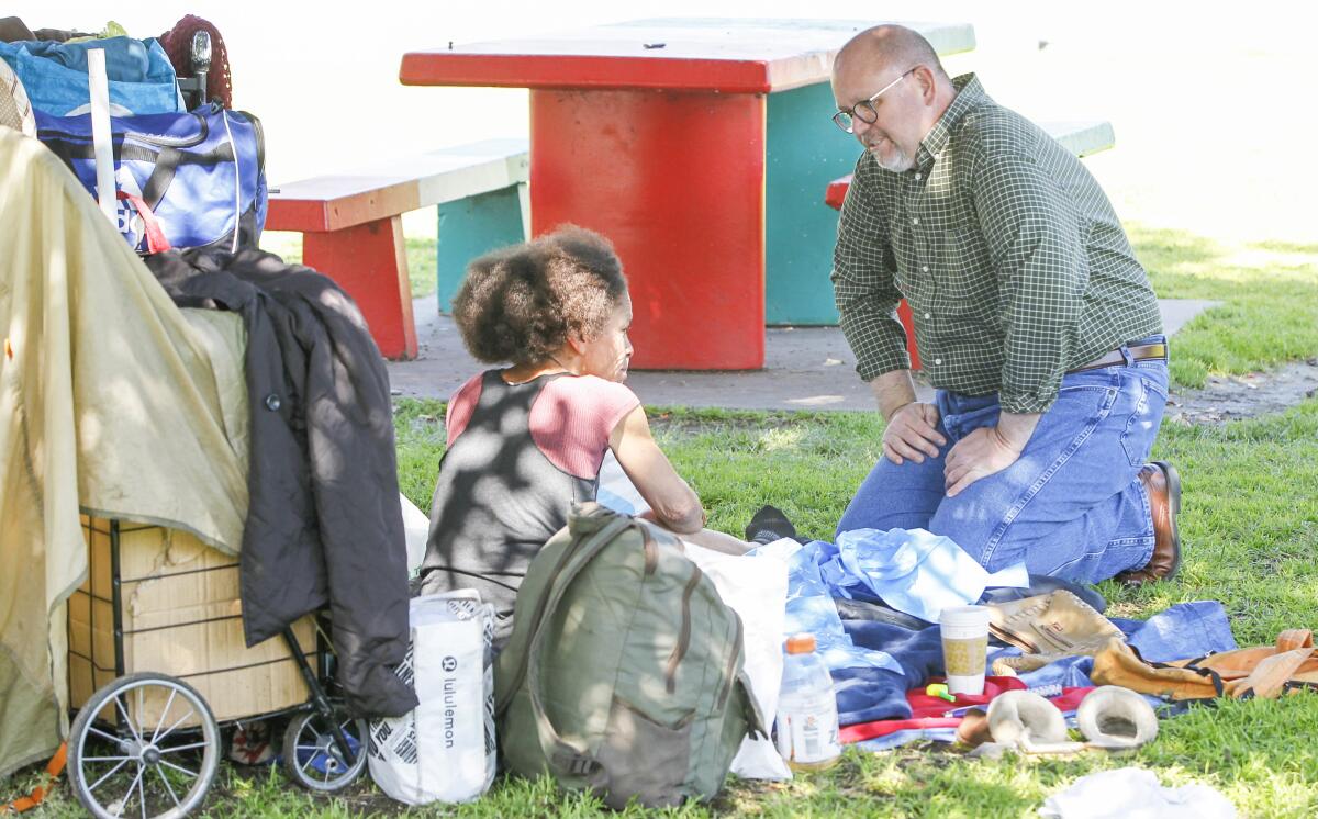 Homeless advocate Michael McConnel (right) hands out trash bags and talks to Gia Lawton about taking precautions to lessen the impact of the Coronavirus at Chicano Park in Barrio Logan on March 6, 2020 in San Diego, California.