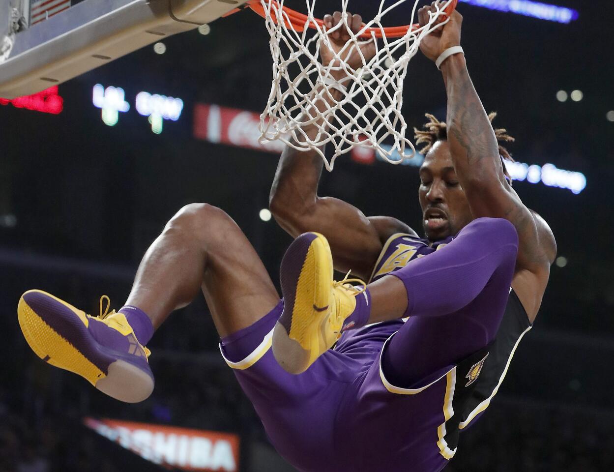 Lakers center Dwight Howard hangs on the rim after a slam dunk against the Warriors in the second quarter.