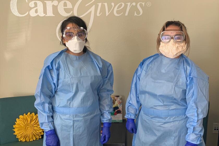 Two caregivers for Homewatch Caregivers in their personal protective equipment, ready to provide care.