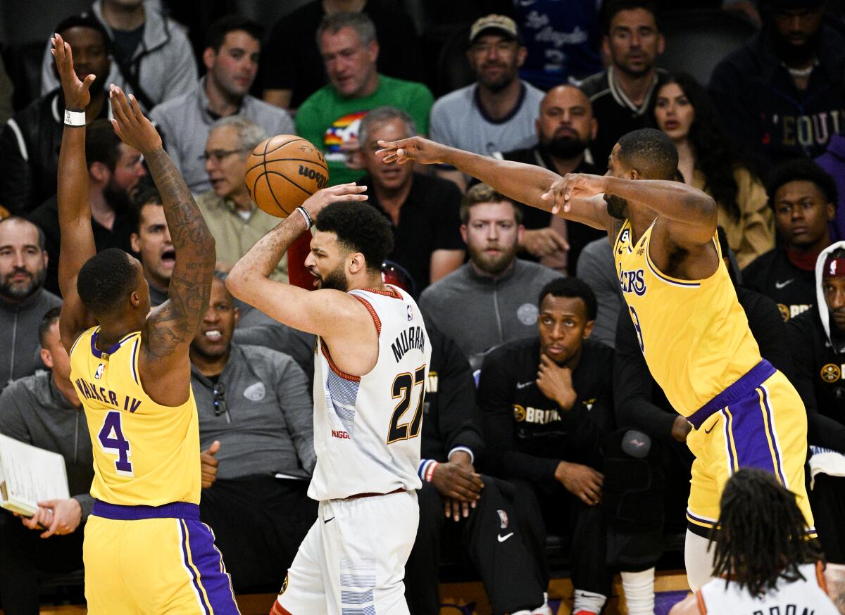 Lakers guard Lonnie Walker IV, left, and center Tristan Thompson, right, play defense against Nuggets guard Jamal Murray.