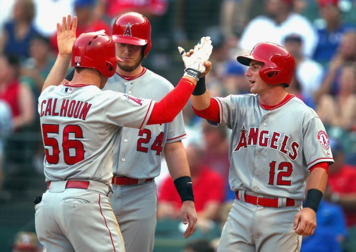 Angels outfielder Kole Calhoun celebrates with C.J. Cron (24) and Johnny Giavotella (12)after hitting a three-run home run against the Rangers.