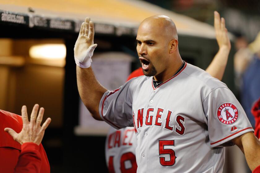 Albert Pujols celebrates with teammates after hitting a grand slam in the seventh inning of the Angels' 12-7 victory over the Oakland Athletics on Friday.