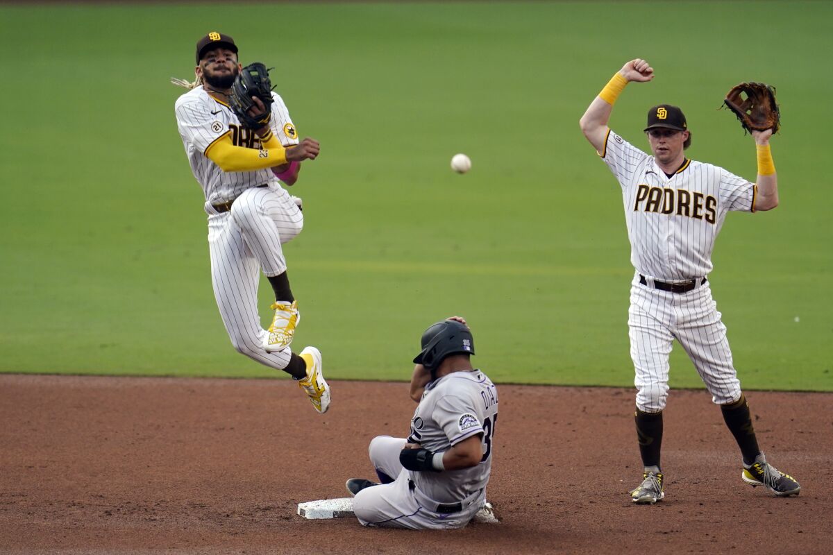 San Diego Padres shortstop Fernando Tatis Jr., left, throws to first too late for the double play as Colorado Rockies' Elias Diaz slides into second base during the second inning of a baseball game Wednesday, Sept. 9, 2020, in San Diego. Padres second baseman Jake Cronenworth is at right. Raimel Tapia was safe at first. (AP Photo/Gregory Bull)