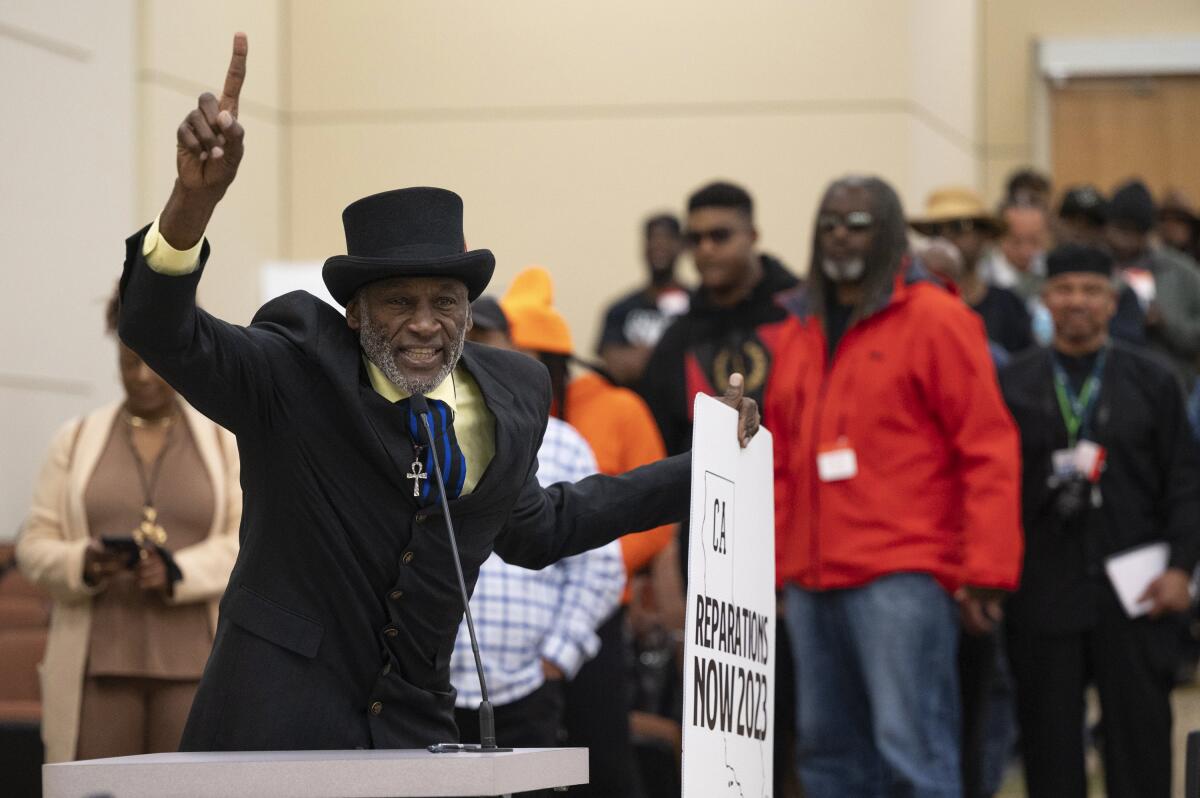 A man in suit and top hat points in the air to emphasize a point at a public comment forum